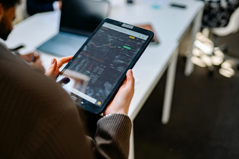 a close up of a person holding a cell phone, in front of a computer, square, charts, best photo