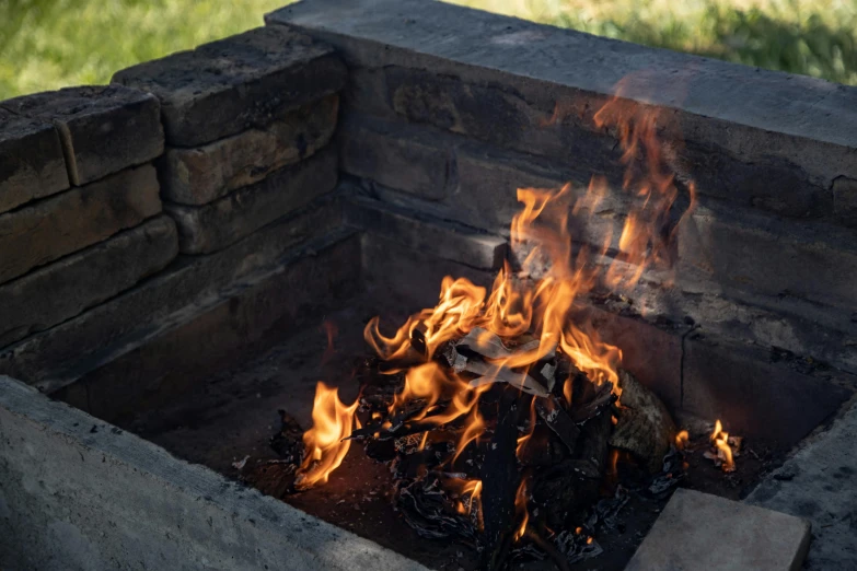 an old brick fire pit that has been turned into a fire pit with flames in it