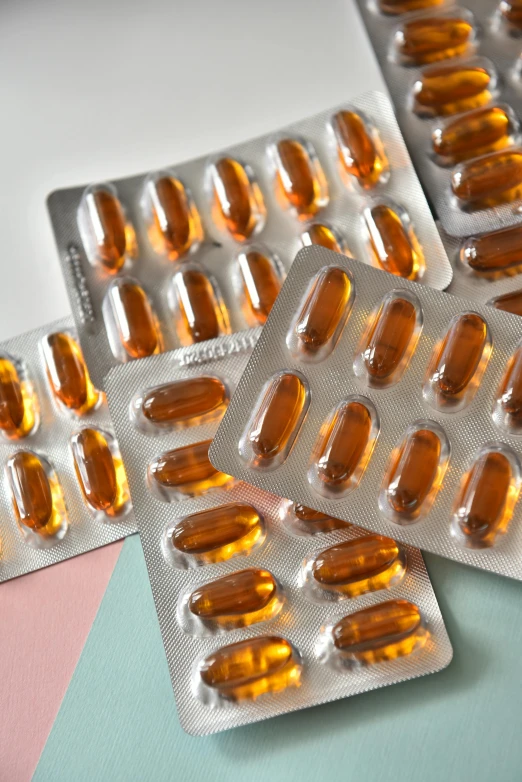 three blister pills lying on a table and one is orange