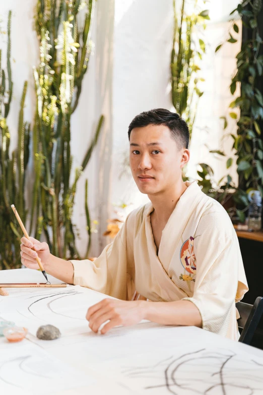 a couple of people that are sitting at a table, a watercolor painting, inspired by Fei Danxu, featured on reddit, visual art, holding a paintbrush in his hand, asian male, architect, 2 3 years old