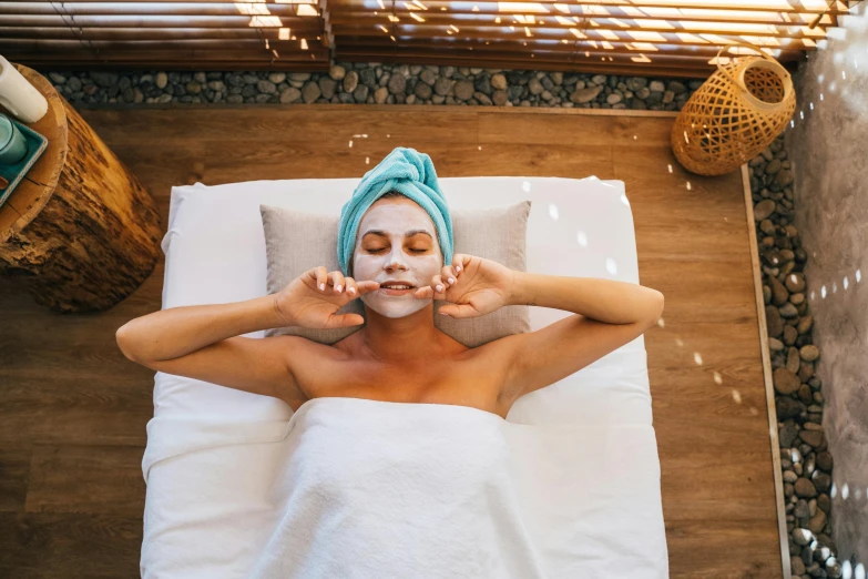 a woman laying on a bed with a towel on her head, pexels contest winner, renaissance, face mask, paradise garden massage, manuka, square facial structure