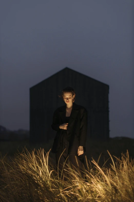 a woman standing in a field at night, an album cover, conceptual art, a man wearing a black jacket, black house, ignant, silo