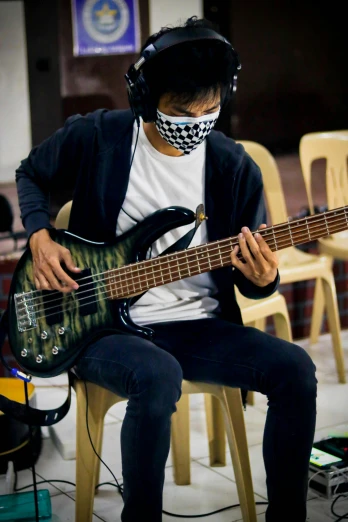 a man sitting on a chair playing a bass guitar, by Robbie Trevino, reddit, wearing facemask, darren quach, profile image, practice