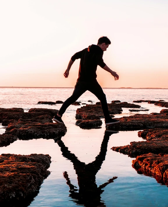 a man walking across a body of water, an album cover, pexels contest winner, happening, stepping stones, lachlan bailey, bouncing, profile pic