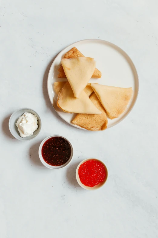 three small bowls of sauce next to a plate with dessert