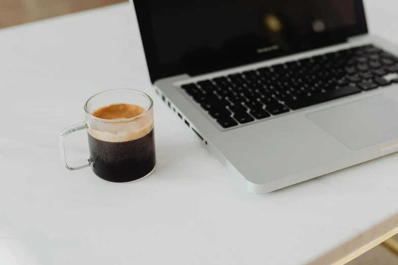 a laptop computer sitting on top of a table next to a cup of coffee, unsplash, black and brown, with a white background, background image, casey cooke