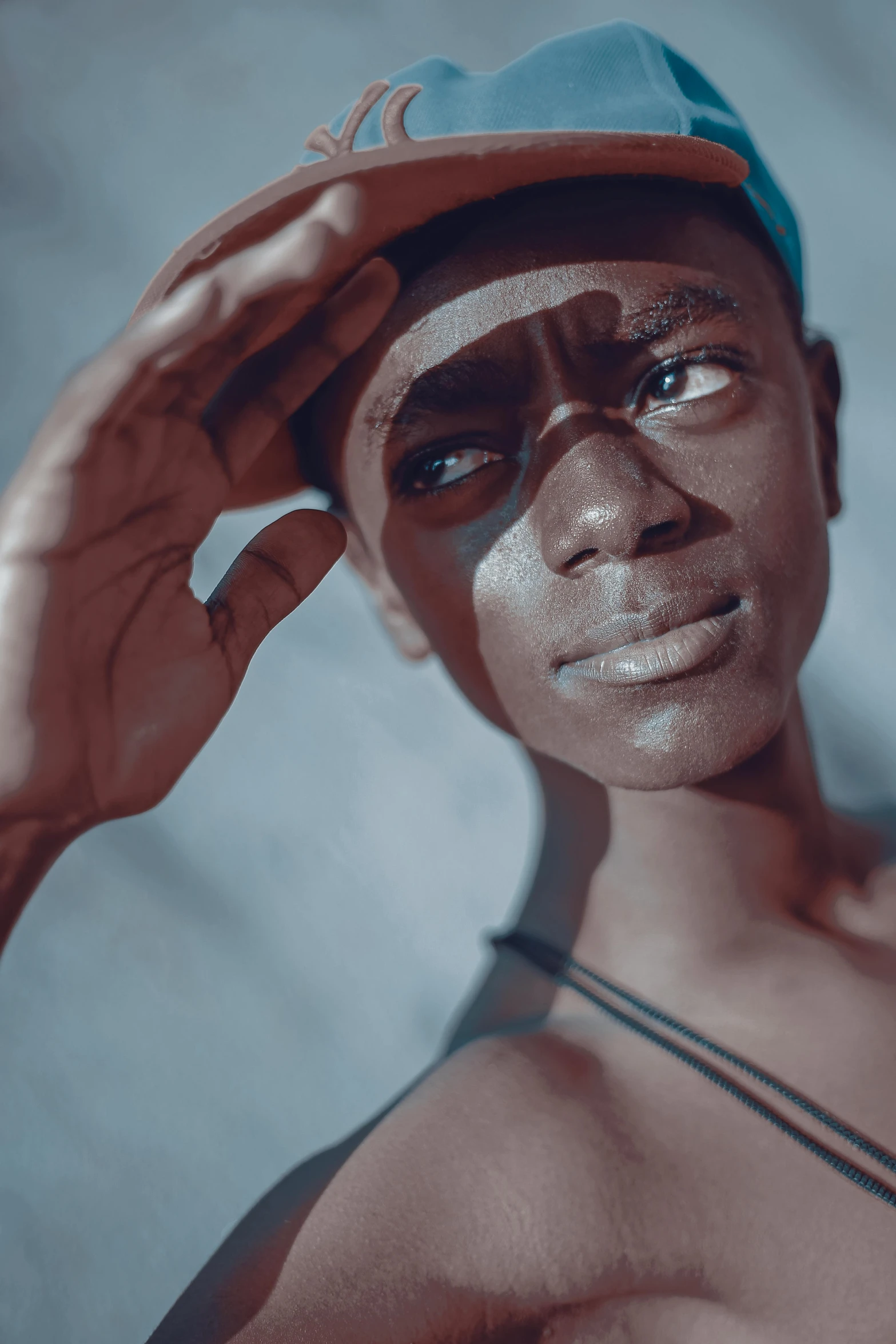 a close up of a person wearing a hat, pexels contest winner, afrofuturism, delicate androgynous prince, sunfaded, yoruba body paint, desaturated blue