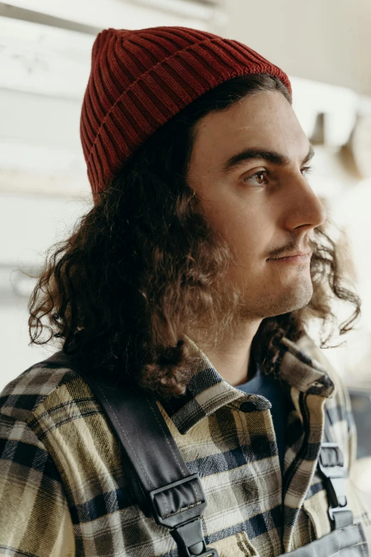 a man with long hair is wearing a red hat