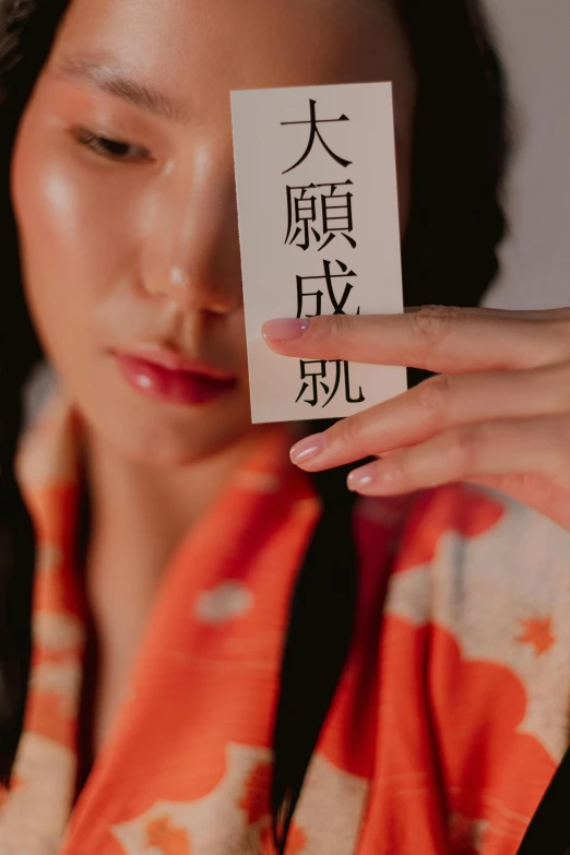 a woman holding up an card with the japanese character's name on it