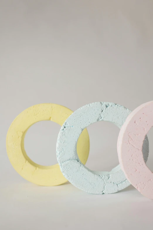 a couple of doughnuts sitting next to each other, inspired by Rachel Whiteread, concrete art, 3 colours, detail shot, bright pastel color, sustainable materials