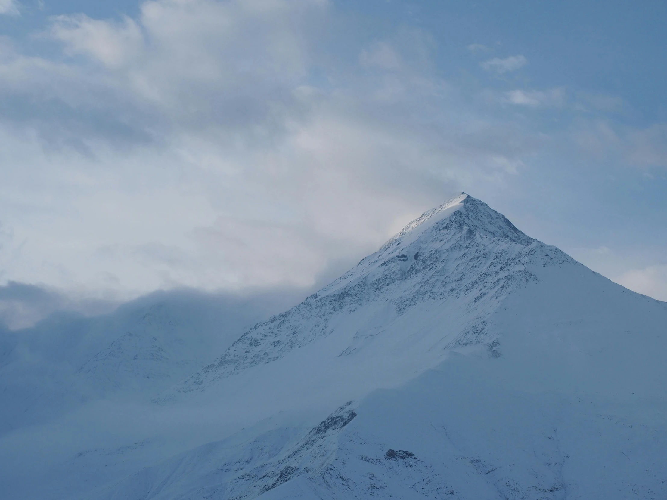 a very tall snow covered mountain on top of a clear day