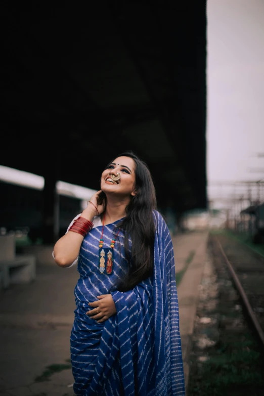 a woman in a blue sari standing on a train track, pexels contest winner, earing a shirt laughing, large)}], profile pic, thick blue lines