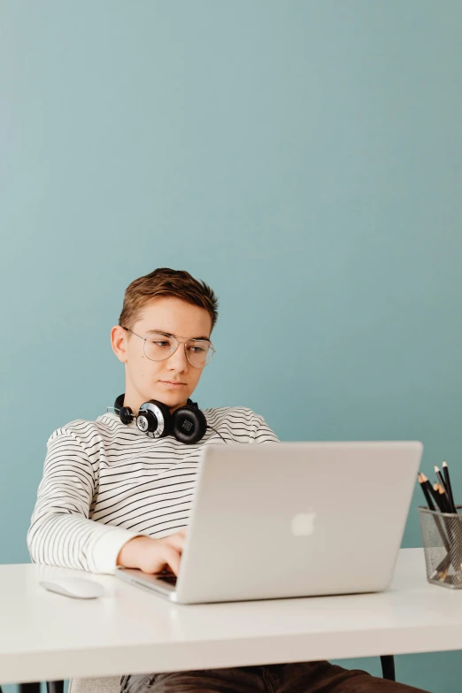 a man sitting at a desk using a laptop computer, trending on pexels, queer woman, wearing stripe shirt, lachlan bailey, studious