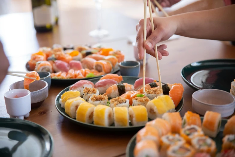 a table topped with plates of sushi and chopsticks, inspired by Maki Haku, trending on unsplash, mingei, medium close up shot, avatar image, multicoloured, about to consume you