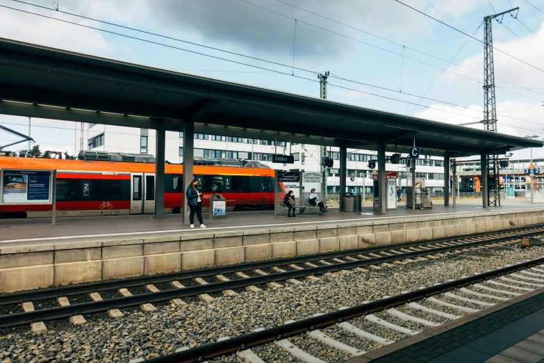 a train pulling into a train station next to a platform, a picture, by Kristian Zahrtmann, unsplash, orange line, square, bus stop, a ghetto in germany