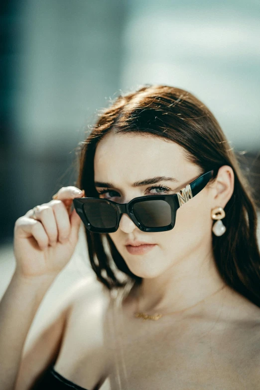 the young woman wears black sunglasses and is looking through her hair