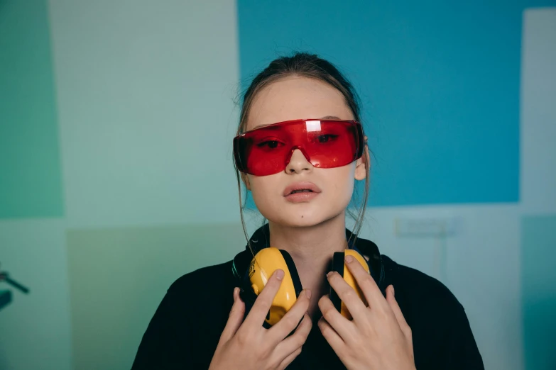 a woman wearing headphones and a pair of red glasses, trending on pexels, pop art, colored lasers, wearing red and yellow clothes, portrait sophie mudd, dark visor covering eyes