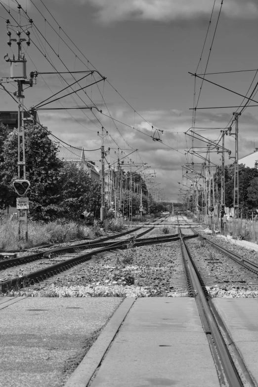 a black and white photo of a train track, hannover, wires everywhere, summer day, taken in 2 0 2 0