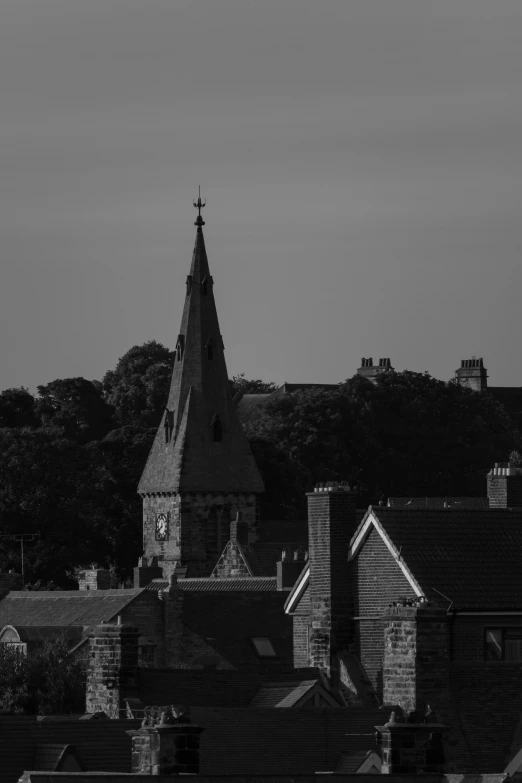 a black and white photo of a church steeple, a black and white photo, by IAN SPRIGGS, unsplash, hiding in the rooftops, late summer evening, town, shot on 1 5 0 mm