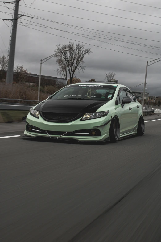 a green and black car is driving down the road