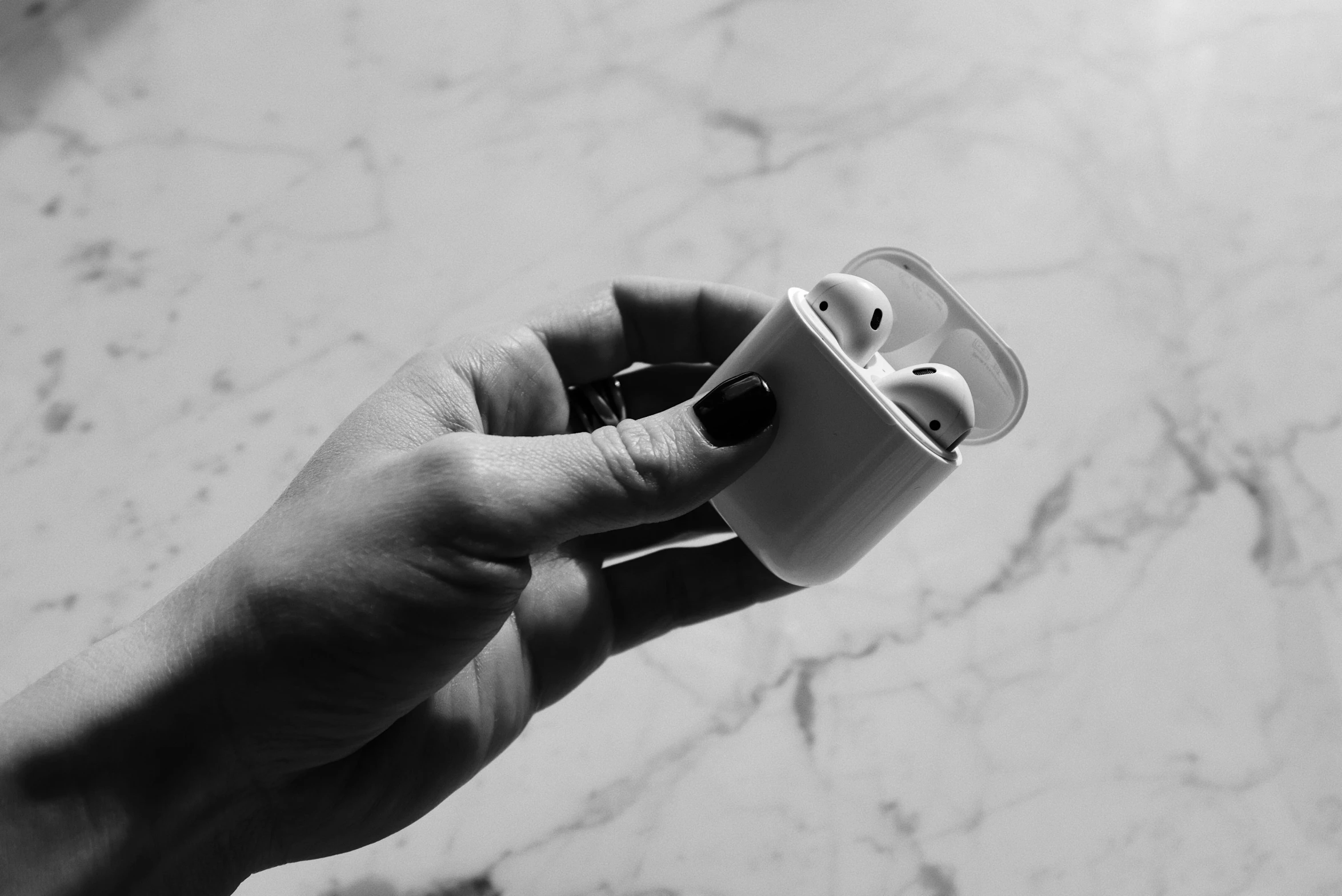 a person holding an airpods in their hand, a black and white photo, by Emma Andijewska, pexels, minimalism, carrara marble, 🤠 using a 🖥, white plastic, apple