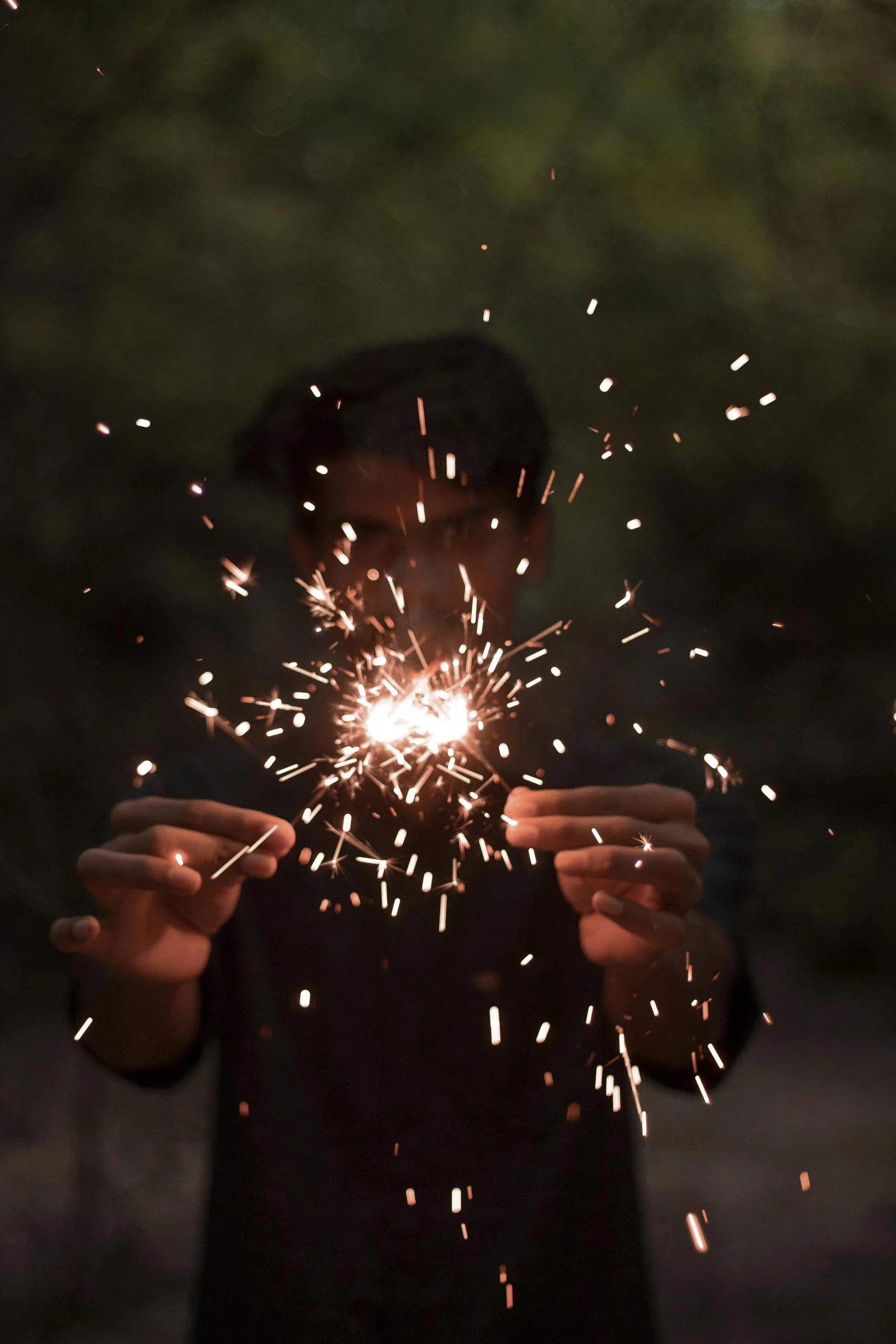 a boy holding a sparkler to show its teeth