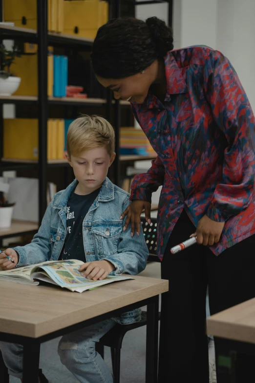a woman helping a young boy with a book, pexels contest winner, ashcan school, hyperrealistic vfx render, standing in class, gif, color corrected
