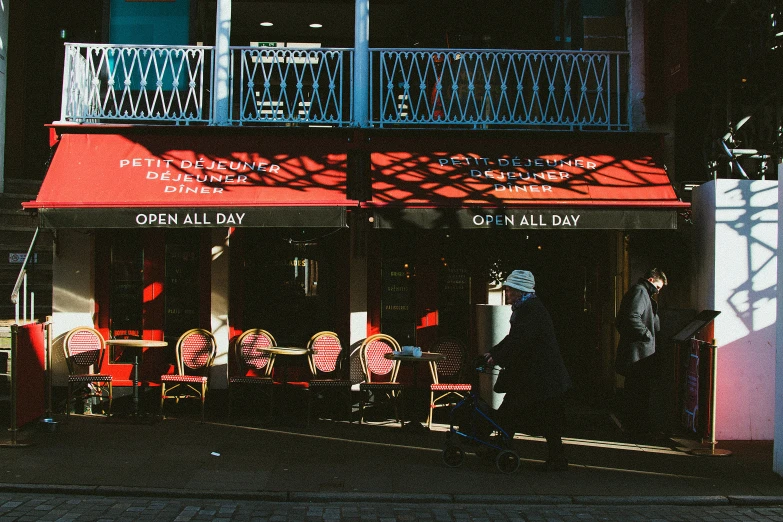 a couple of people that are standing in front of a building, by Peter Churcher, pexels contest winner, visual art, cafe tables, black and red colour palette, exiting store, outside a saloon