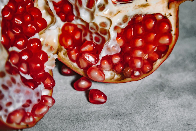 a close up of a pomegranate cut in half, by Julia Pishtar, trending on pexels, on grey background, corals are gemstones, 🦩🪐🐞👩🏻🦳, inside a cavernous stomach
