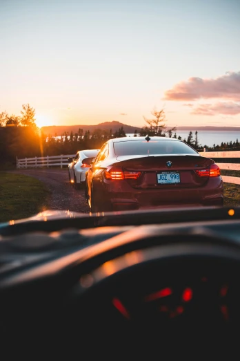 a car driving down a road next to a fence, by Matt Cavotta, pexels contest winner, sunset panorama, bmw, quebec, back to back