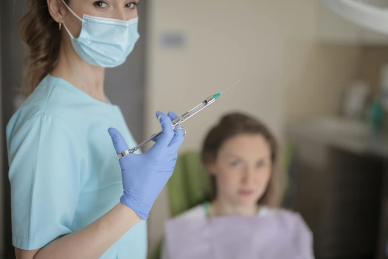 a woman in a blue shirt is holding a sys, a picture, by Adam Marczyński, shutterstock, hurufiyya, holding syringe, dentist, 15081959 21121991 01012000 4k, facemask