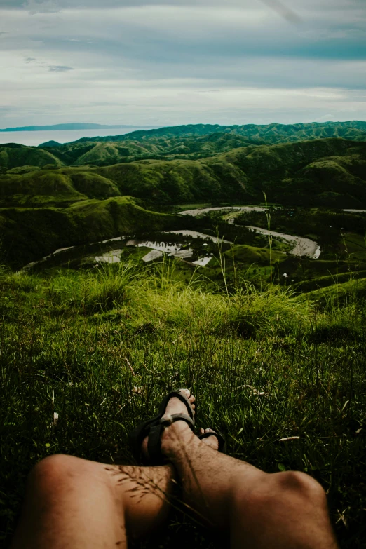 the feet of a person laying in the grass on top of a hill