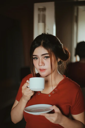 a woman in a red shirt holding a plate and a cup, by Basuki Abdullah, pexels contest winner, realism, pouty face, 🤤 girl portrait, white mug, soft warm light