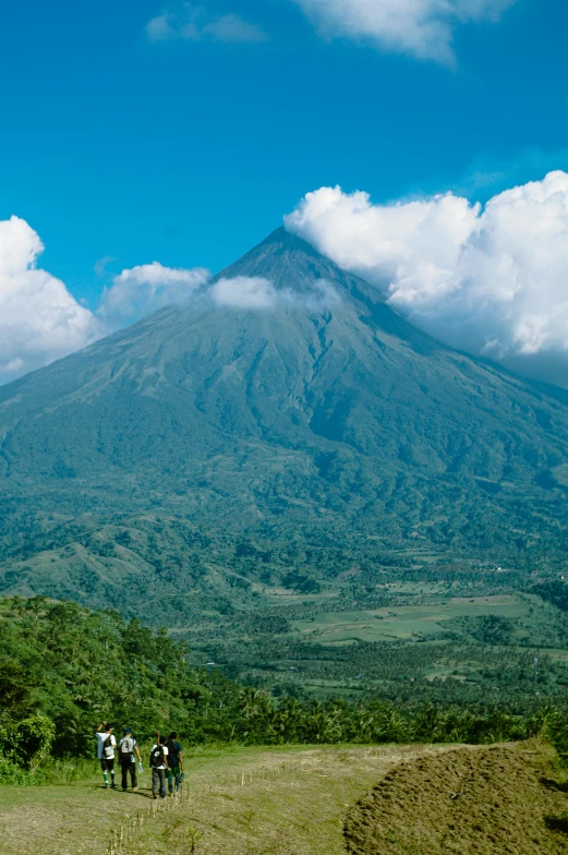 four people standing on a hill near a large mountain