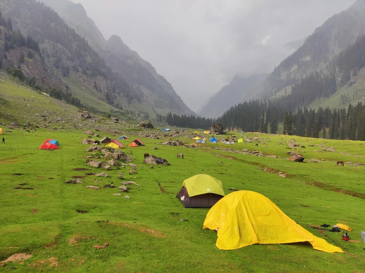 a group of tents sitting on top of a lush green field, by Muggur, pexels contest winner, hurufiyya, avatar image, leaking, yellow, high elevation