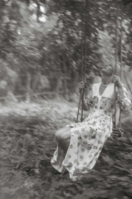 a woman sitting on a swing in the woods