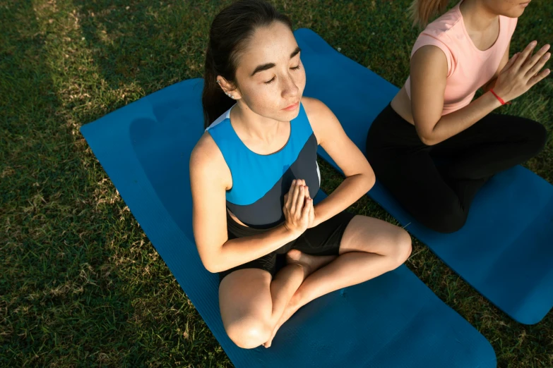 two women practice yoga while sitting on their exercise mats