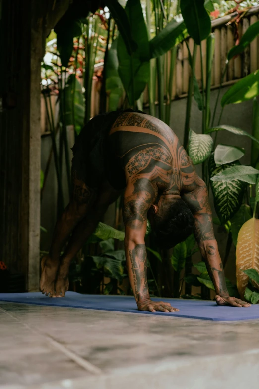 a man doing a handstand pose on a yoga mat, a tattoo, in the jungle. bloom, profile image, still from film, gardening