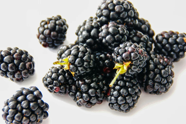 a pile of ripe blackberries sitting on top of a white table