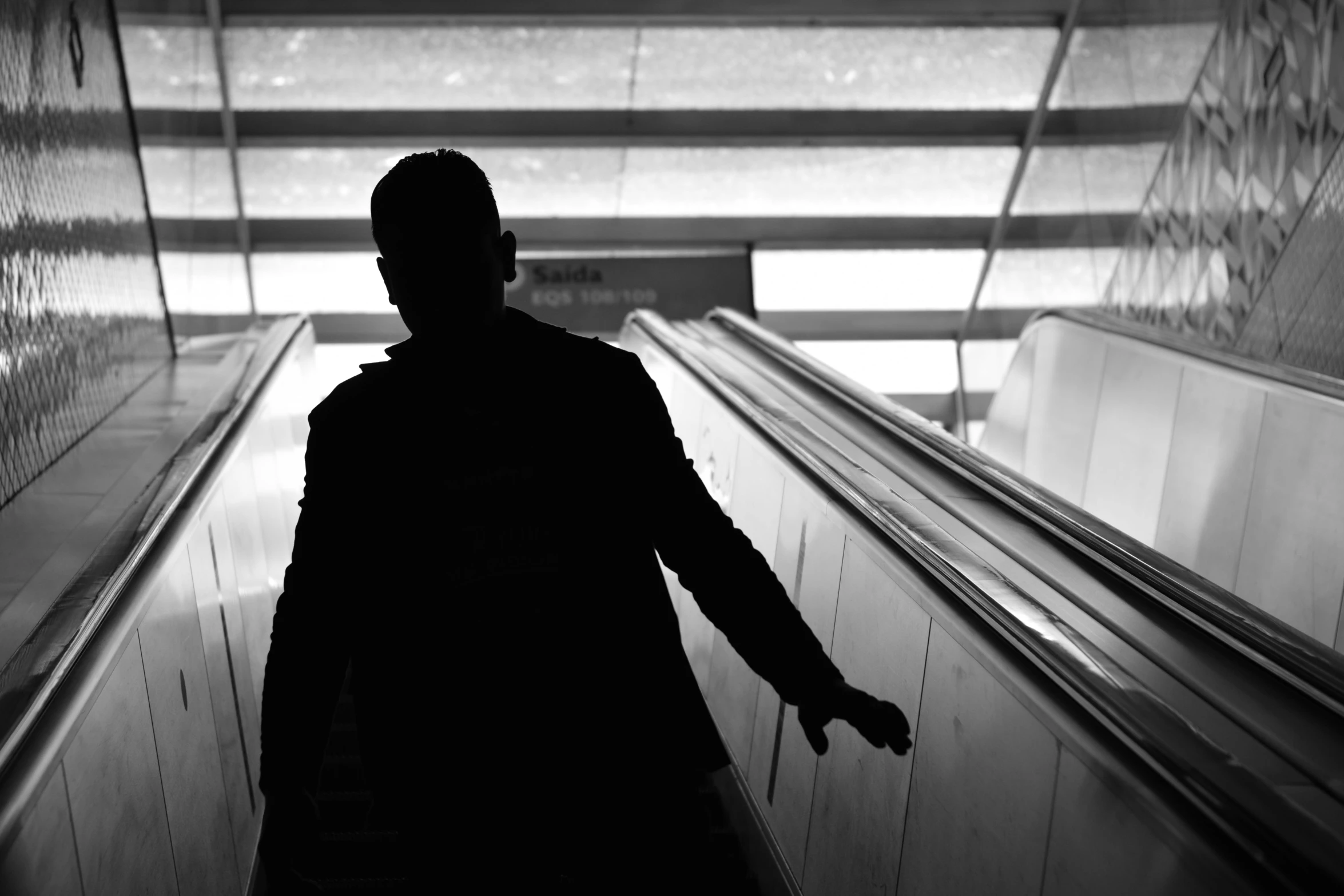 a black and white photo of a person on an escalator, silhouette of a man, facebook photo, phot, thumbnail