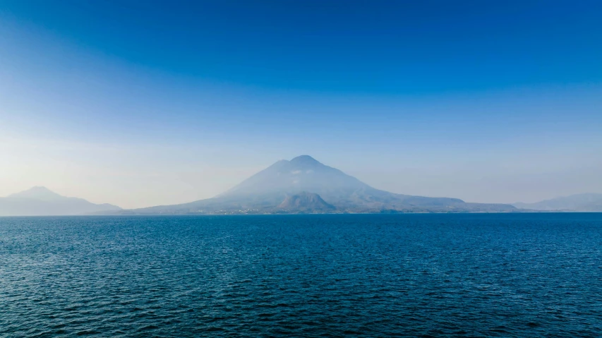 two very tall mountains over water with clouds