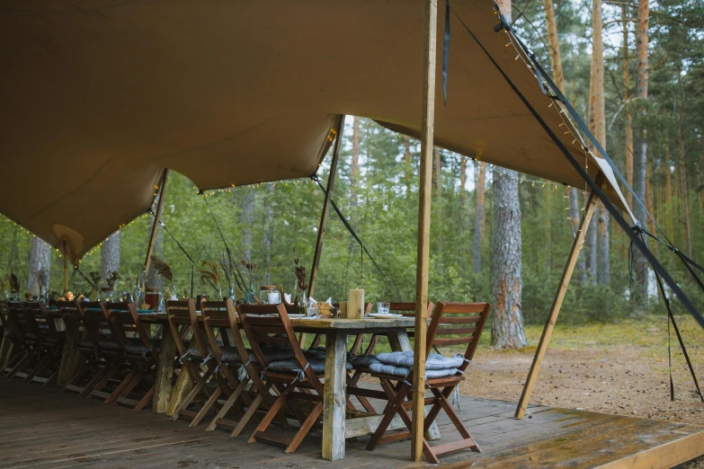 a large tent set up in the middle of a forest, unsplash, process art, dining table, finnish naturalism, brown, deck