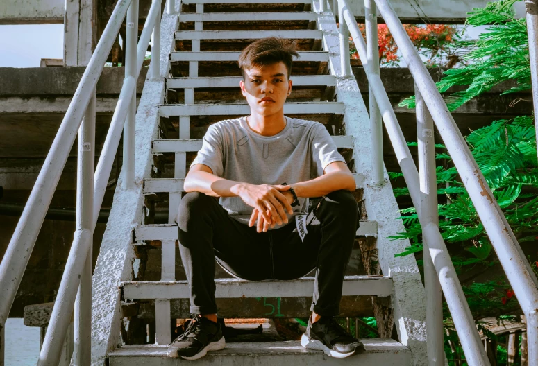 a young man sitting on a staircase next to some plants