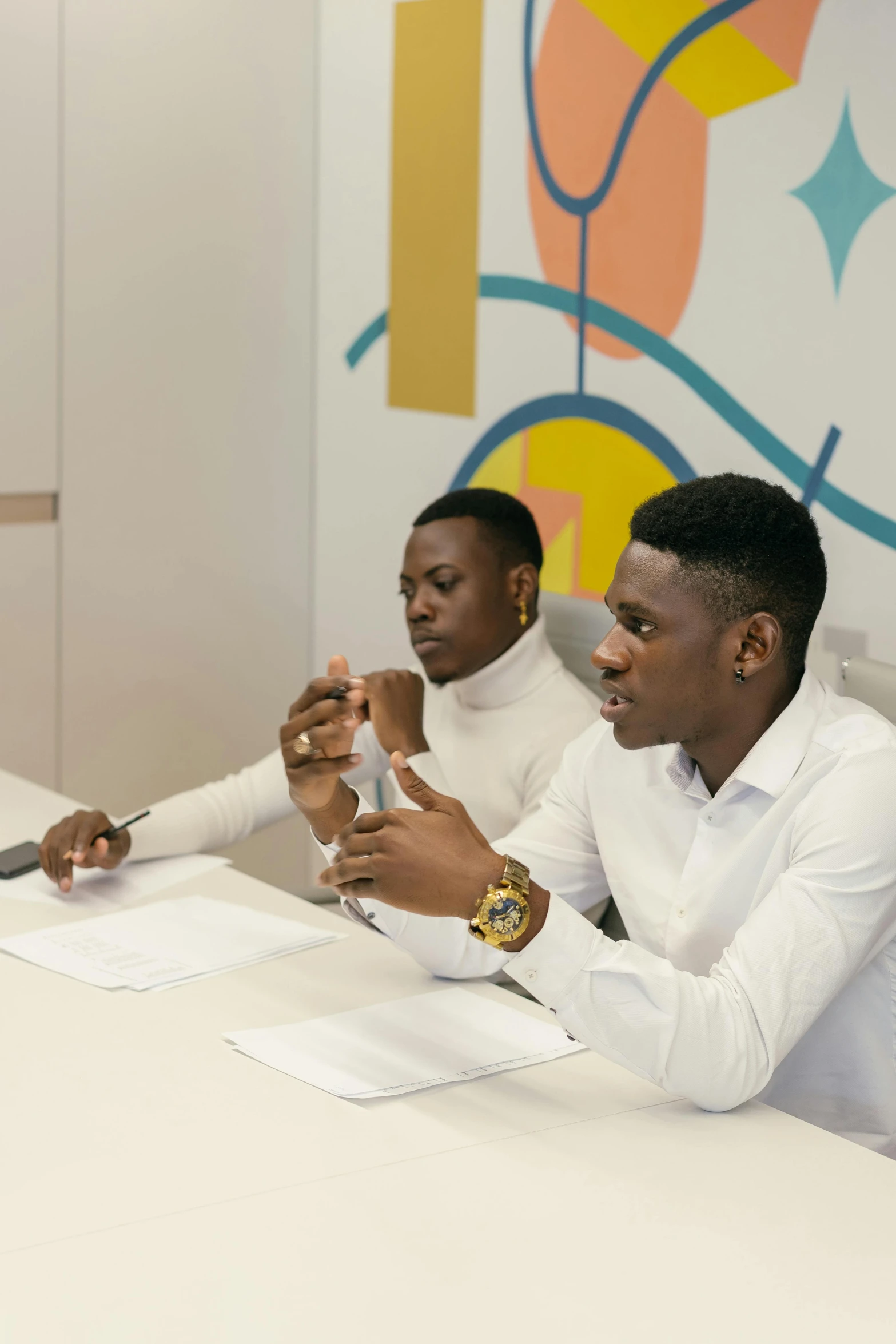 a group of men sitting around a table, on a white table, adebanji alade, confident looking, two young men