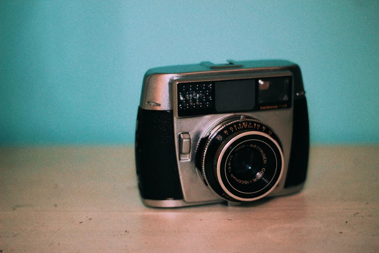 an old camera is displayed in front of a blue wall