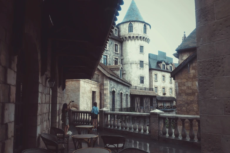 a couple of tables sitting on top of a balcony, inspired by Gaston Bussière, pexels contest winner, gothic castle, rainy; 90's photograph, town square, medieval times