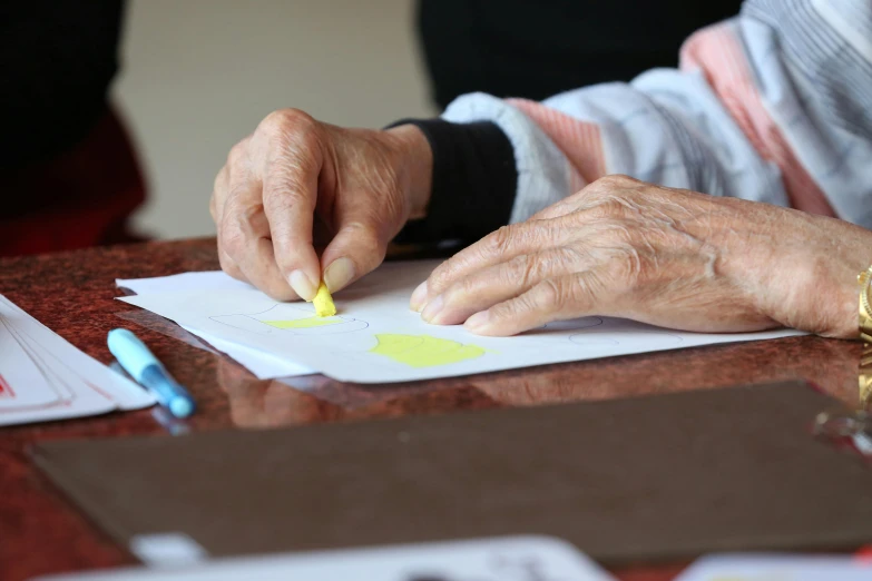 a close up of a person writing on a piece of paper, nursing home, lady using yellow dress, mate painting, finger painting