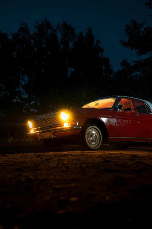 a red car sitting on top of a forest covered road