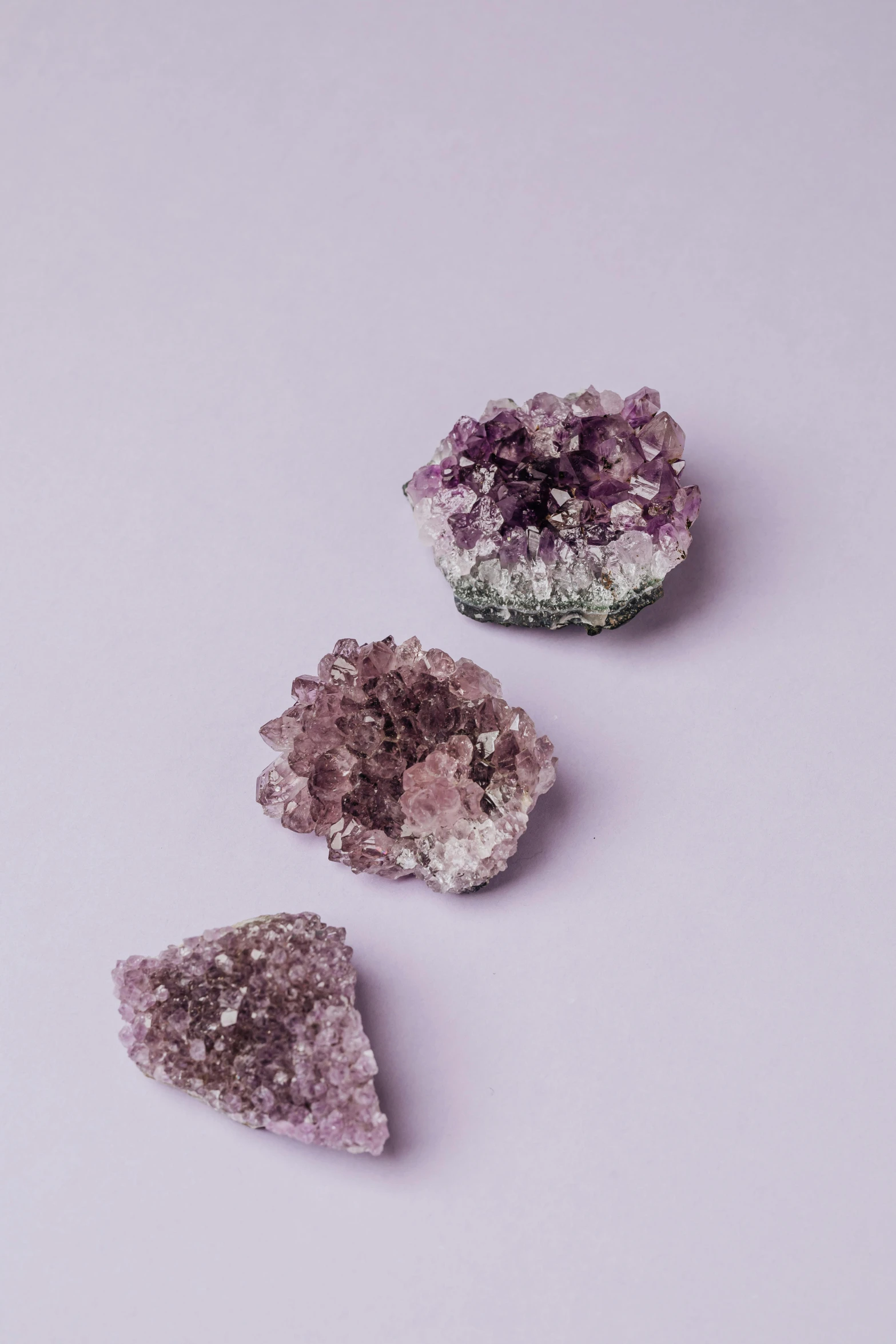 three pieces of amethorate on a white surface, trending on pexels, crystal cubism, ((purple)), super natural, shui mo hua, earthy