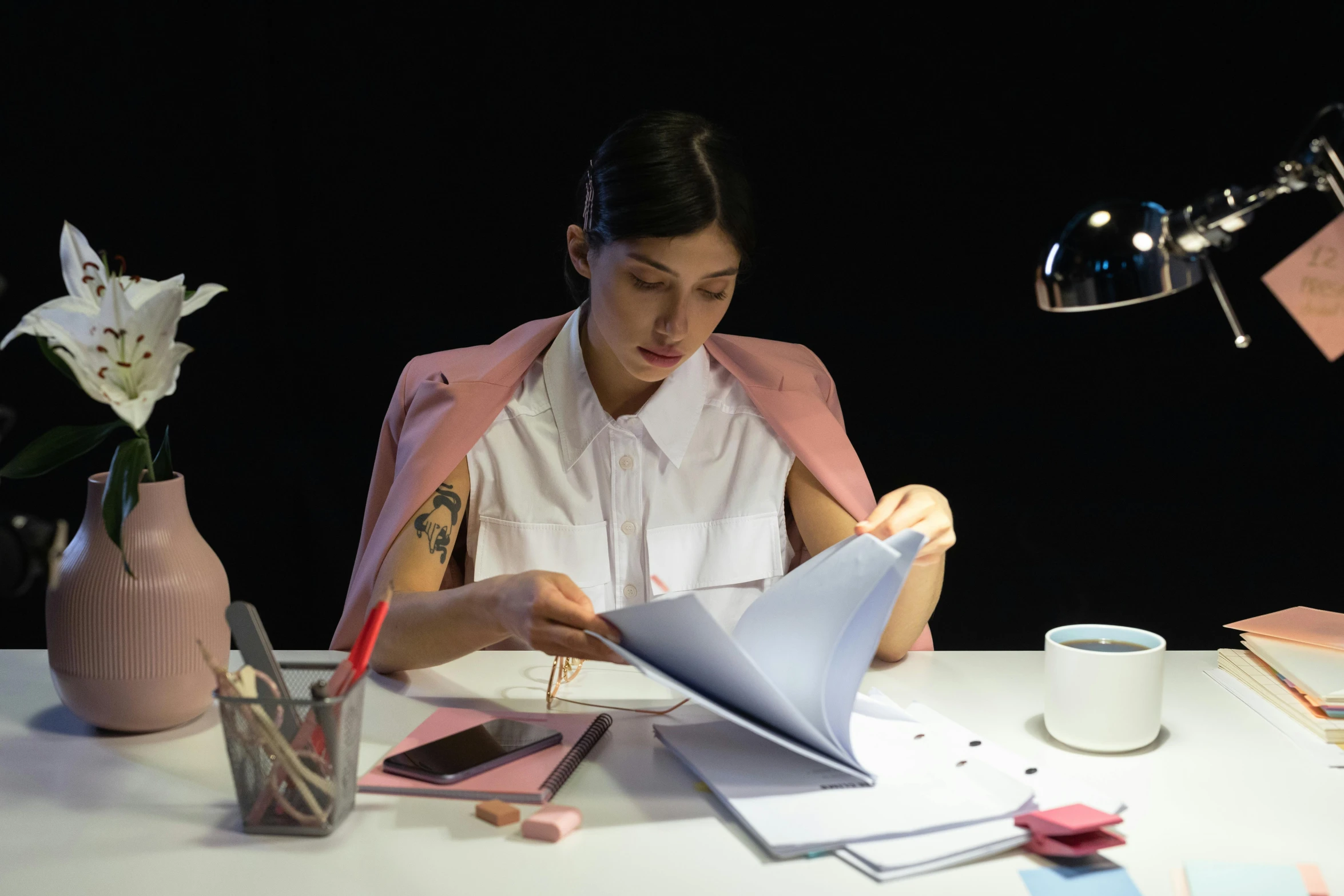 a woman sitting at a desk reading a book, pexels contest winner, hyperrealism, fashion designer, low - lighting, video still, engineer